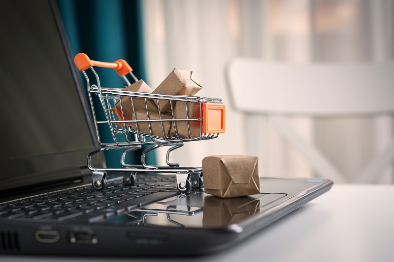 A mini push cart filled with mini boxes on the top of laptop's keyboard